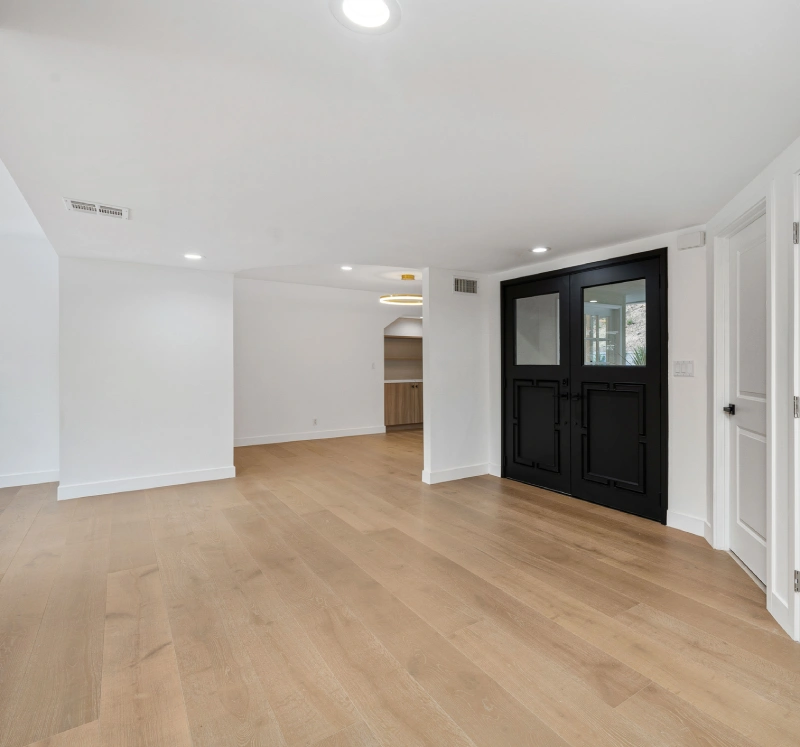 Spacious room with wooden floor and door.